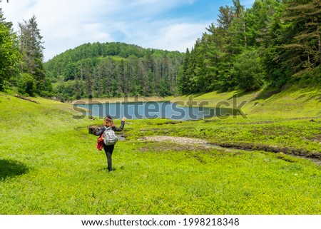 A young woman walking through the Domiko reservoir, a lake with pine trees around it and beautiful spring flowers. A reservoir in Navarra next to Lesaka