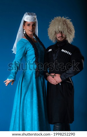 Full height Georgian folk dancers couple posing on blue. High quality picture of authentic Caucasian dancers performing on dark blue matte background