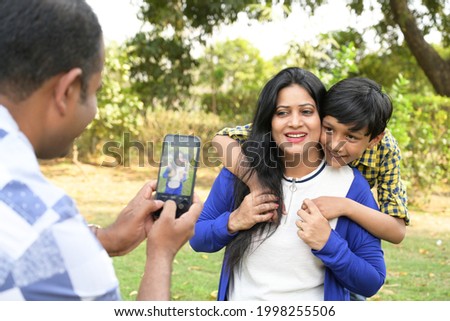A father is taking photo of his wife and son in the park