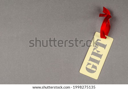 Concept of percentage label for sales promotion. Yellow textured sales tag on gray background. Paper rectangular tag with red ribbon vertically under slant. Copy space.