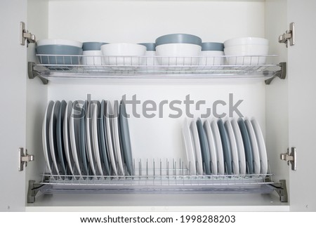 White and gray plates are stacked for storage in the kitchen Royalty-Free Stock Photo #1998288203