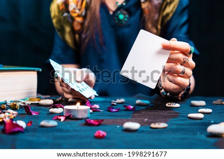 The fortune teller shows an empty white tarot card. Mock up. Copy space. Cartomancy and fortune telling. Royalty-Free Stock Photo #1998291677