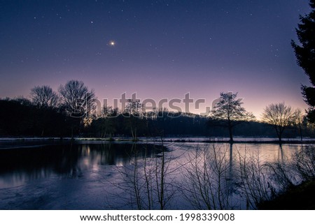 Dusk at winter evening with stars and venus on the night sky at lake landscape with silhouettes trees and reflection Royalty-Free Stock Photo #1998339008