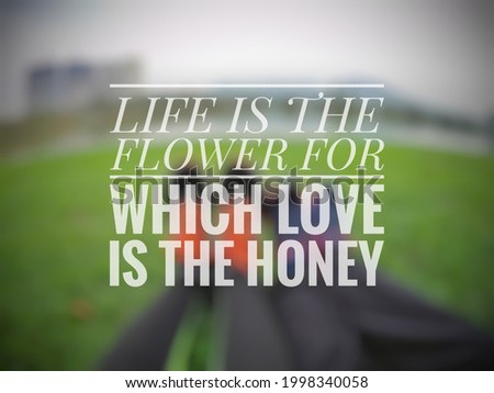 Inspirational love quote "LIFE IS THE FLOWER FOR WHICH LOVE IS THE HONEY" isolated on a blurry background.