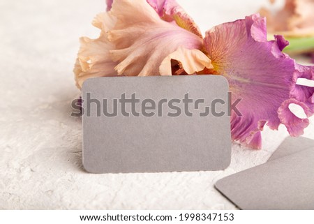 Gray business card with iris purple flowers on white concrete background. side view, copy space, mockup, template, spring, summer minimalism concept.