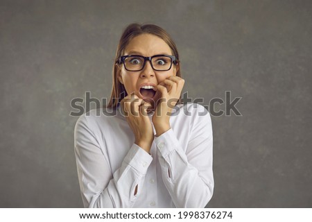 Young woman panicking. Studio portrait of office worker in white shirt and glasses screaming loudly scared by something terrible, witnessing awful crime, or afraid of danger. Fear and fright concept Royalty-Free Stock Photo #1998376274
