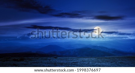 mountain meadow at night. beautiful landscape with clouds above horizon in full moon light. wonderful nature background