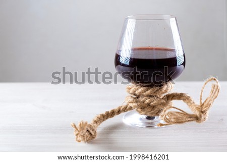 glass of red wine is tied with a rope. The concept of alcohol addiction. copy space