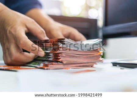 Pile of presentation brochure document concept : Businessman hands working in business Documents on Stacks Brochures papers files for checking achieves reports on busy work computer desk office Royalty-Free Stock Photo #1998421499