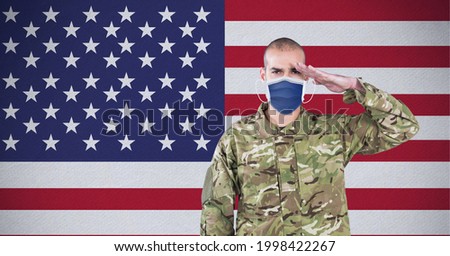 Composition of saluting male soldier wearing face mask, against american flag. patriotism, independence and military during covid 19 pandemic concept digitally generated imag