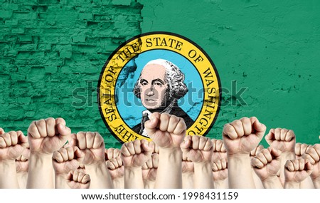 Raised fists of men against the background of the flag of State of Washington painted on the wall, the concept of popular unity and the opinion of the majority.