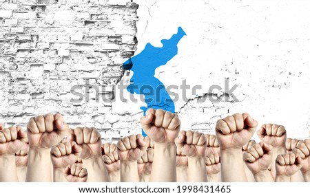 Raised fists of men against the background of the flag of Korean Unification painted on the wall, the concept of popular unity and the opinion of the majority. Royalty-Free Stock Photo #1998431465