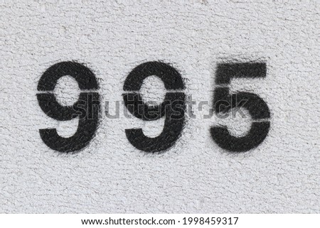 Black Number 995 on the white wall. Spray paint. Number nine hundred ninety five.