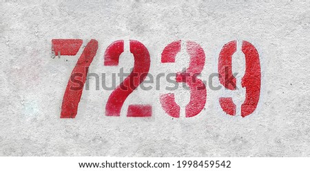 Red Number 7239 on the white wall. Spray paint. Number seven thousand two hundred thirty nine.