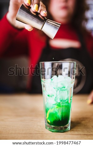 A girl prepares mint lemonade - a bright summer green drink with refreshing mint and lemon sourness