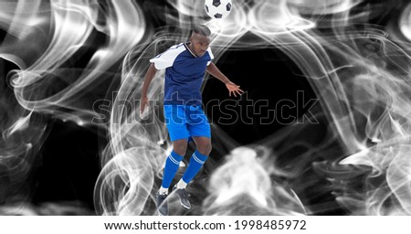 Composition of male football player with ball on black background. sport and competition concept digitally generated image.
