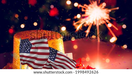 Composition of lit sparkler with american flags. patriotism, independence and celebration concept digitally generated image.