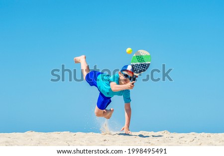 Young boy playing tennis on beach. Summer sport concept
