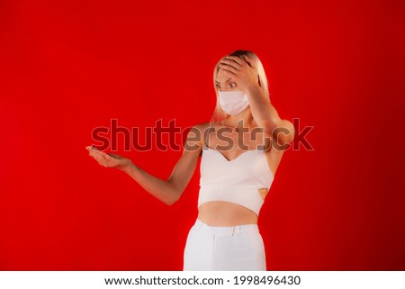 Copy space photo of slim blonde in white medical mask and white outfit on matte red background. Health and anti-pandemic concept.
