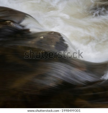 Beautiful fine art landscape image of long exposure detail of fast flowing water over rocks in river