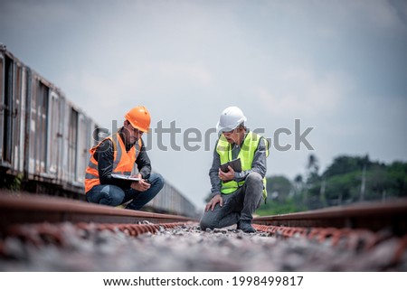 Engineers under discussion inspection and checking construction process railway switch and checking work on railroad station .Engineer wearing safety uniform and safety helmet in work. Royalty-Free Stock Photo #1998499817