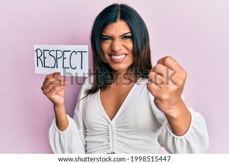 Young latin transsexual transgender woman holding respect message paper annoyed and frustrated shouting with anger, yelling crazy with anger and hand raised 