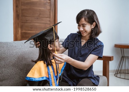 Kindergarten graduation. Asian mother and kid preparing on her kinder graduate day at home