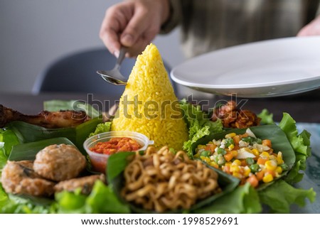 nasi tumpeng. indonesian cuisine yellow rice on banana leaf for celebration Royalty-Free Stock Photo #1998529691