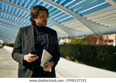 Middle age businessman with relaxed expression using smartphone at the city.