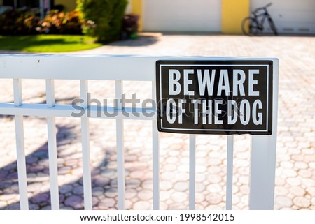 Beware of the dog sign on white fence gate railing in residential neighborhood house home in Hollywood, Florida Broward County North Miami Beach