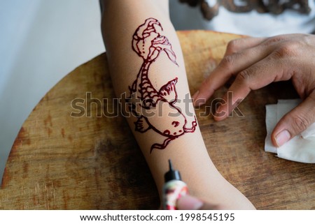 Painting henna ornaments on girl's hand closeup.