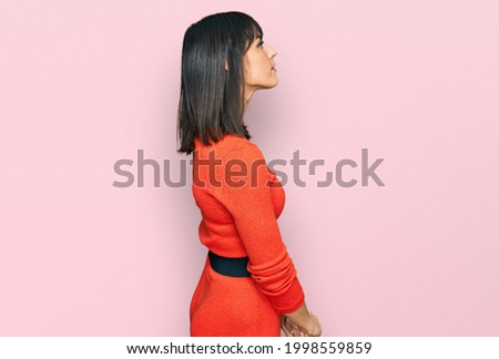 Young hispanic woman wearing casual clothes looking to side, relax profile pose with natural face with confident smile. 