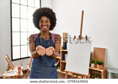 Young african american woman with afro hair at art studio smiling with hands palms together receiving or giving gesture. hold and protection 