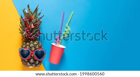 Hipster pineapple in sunglasses and bright beads.Paper cup with cocktail tubes Minimal concept, summer tropical pineapple.Summer, vacation, party