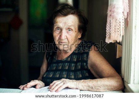 An old woman, a portrait in her house. Royalty-Free Stock Photo #1998617087