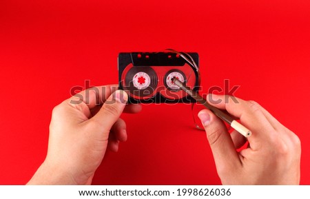 Hand rewinding an old cassette tape with a pencil