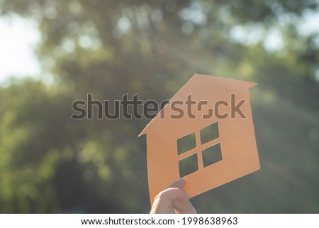 Paper mock-up of a house in the rays of the sun. Get the long-awaited housing, apartment, house.