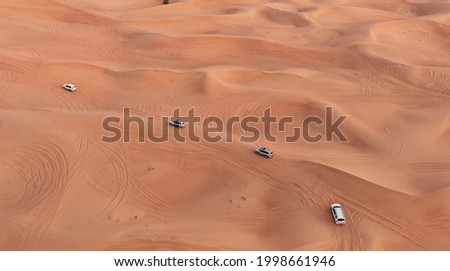 AERIAL. Column of white cars travelling in sand desert. Royalty-Free Stock Photo #1998661946