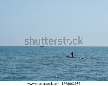 Man on sapsurf in the sea under clear skies on a sunny afternoon