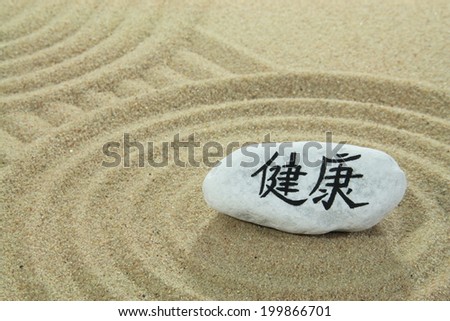 stone onto sand with patterns and the asian word healthiness