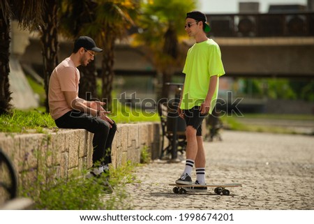 Two friends are talking in park on sunny day.