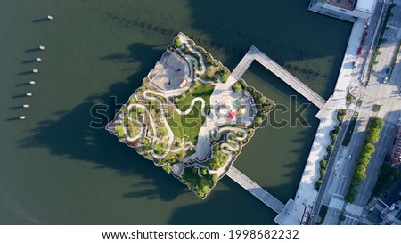 An aerial view over Manhattan's new Little Island. A green space that looks like it's floating on the water of the Hudson River. Taken at sunrise with a drone while the river was calm. Royalty-Free Stock Photo #1998682232