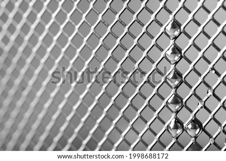 Drops of water on a metal fence in black and white. Macro photography Royalty-Free Stock Photo #1998688172