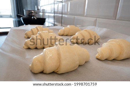 Croissant unbaked fresh on board with baking paper for homemade breakfast