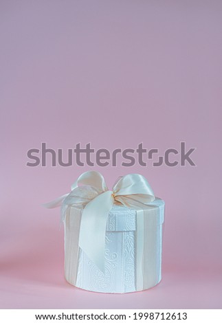 White gift box with white  ribbon on pink background.Greeting card with copy space.