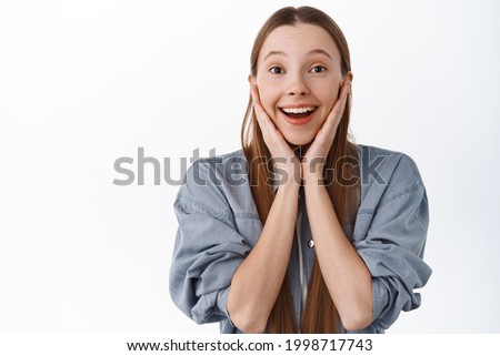 Impressed teenage girl look with fascinated face, admire something beautiful, look at amazing awesome thing, smiling excited, standing over white background