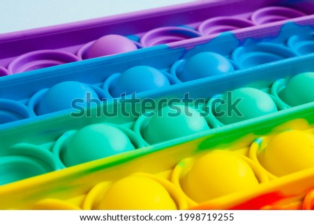 Close-up of the popular children's toy pop It fidget with soft focus. Macro. Soft focus. Anti-stress. New popular silicone colorful pop It game in the form of rectangular isolated on a blue background Royalty-Free Stock Photo #1998719255