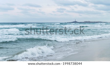 Stormy Mediterranean sea, lighthouse in the distance. Overcast in Mediterranean sea, la Manga del Mar Minor, Spain. 