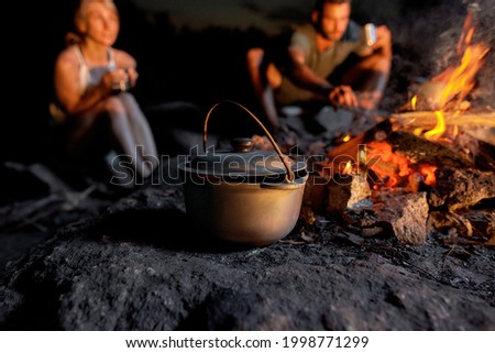 Close up shot of a cauldron. Cooking dinner in field conditions, boiling pot at the campfire. Outdoor adventure, tourism concept. Selective focus Royalty-Free Stock Photo #1998771299