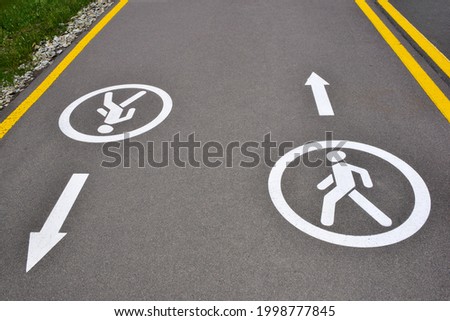 On the asphalt road there are signs for pedestrians in both directions, allowing traffic for walking on the sidewalk